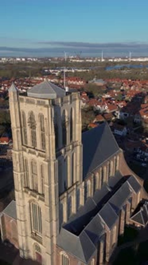 Aerial view of a historic town with a tall Gothic church in the center. Red-roofed houses