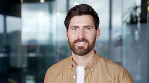 Porträt eines lächelnden gutaussehenden Geschäftsmannes, der am Arbeitsplatz in einem Geschäftsbüro steht. Headshot