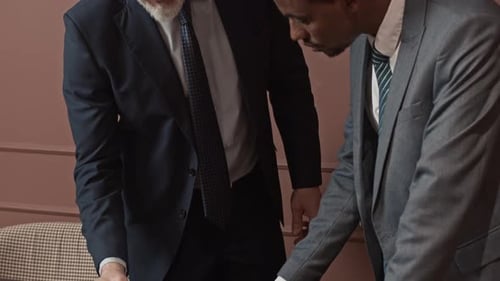 Diverse Businessmen Examining and Signing Agreement at Office Table