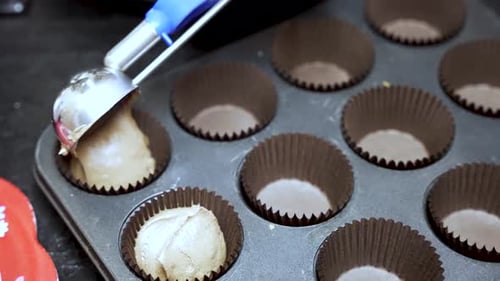 Scooping Cupcake Batter Into Lined Tray for Baking