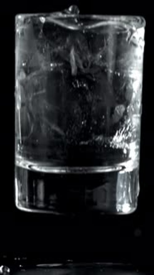 Wodka in einem Glas fällt auf den Tisch, gefilmt mit einer Hochgeschwindigkeitskamera mit 1000 Bildern pro Sekunde