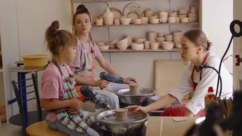 Three People Learn Pottery Techniques at a Studio in a Creative Workshop
