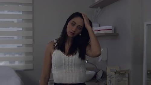 Latina woman in a doctor's office looking pensively at the camera