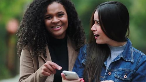 Two Young Women Chatting and Looking at Phone