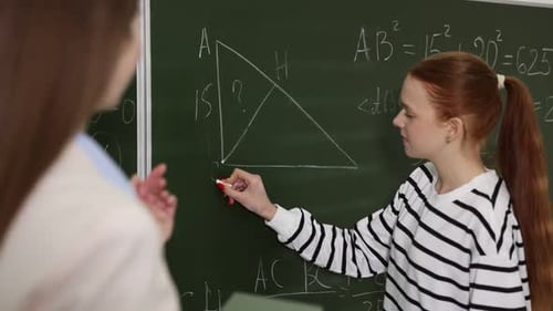 Teen Girl Solving Math Problem on Chalkboard at School