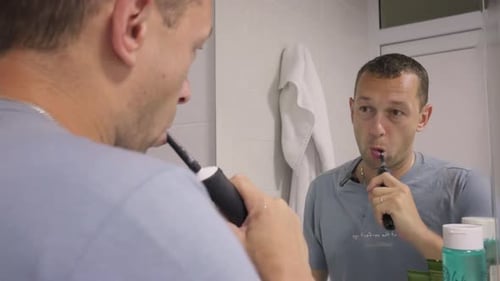 Shot of young man brushing his teeth at home.