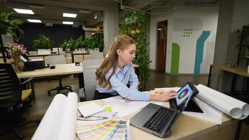 Female Interior Designer Working on Project with Color Palette and Blueprints