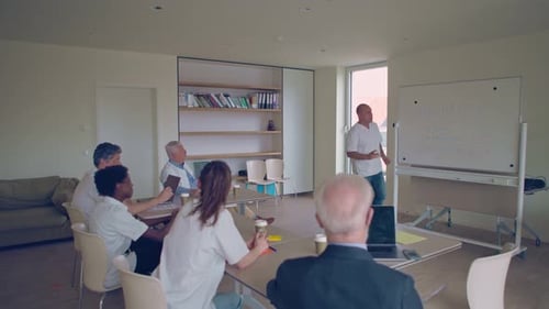 medical doctor giving workshop on hospital care management to colleagues in meeting