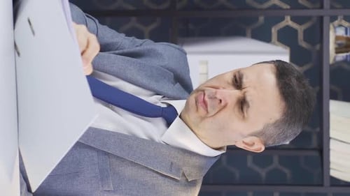 Vertical Video of Serious and focused mature businessman looking at paperwork files in office.