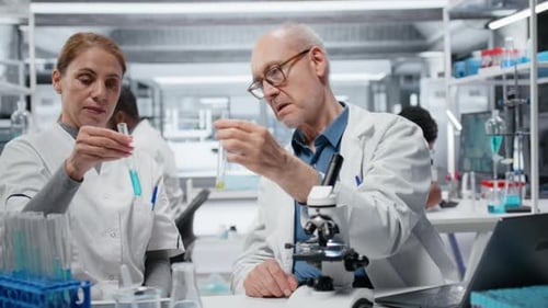 Chef d'équipe de laboratoire enseignant à un stagiaire l'analyse des propriétés des polymères liquides