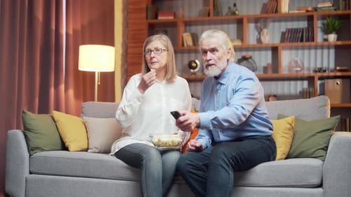 Senior Couple Watching TV and Eating Popcorn