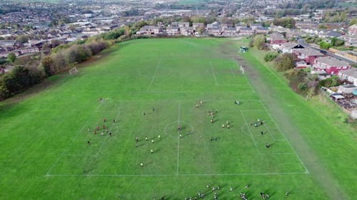 Aerial drone video of extensive playing fields situated on the summit of a hill. Showing football pl