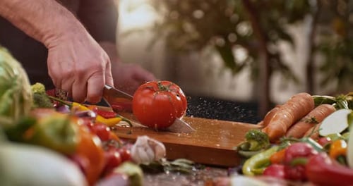 Male chef cutting a tomato