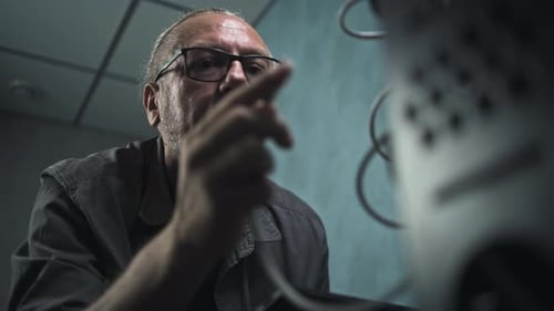 Adult Man Working on Machine in Dark Room