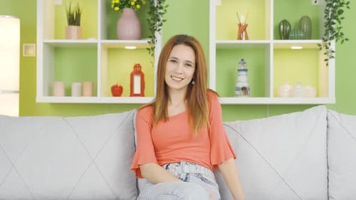 Smiling Young Woman on Gray Couch Indoors