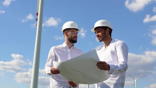 Two Multiracial Windmill Engineers Inspection and Progress Check Wind Turbine