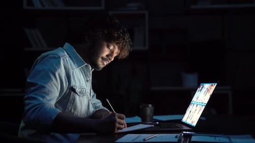 Man video conferencing at night in dark room