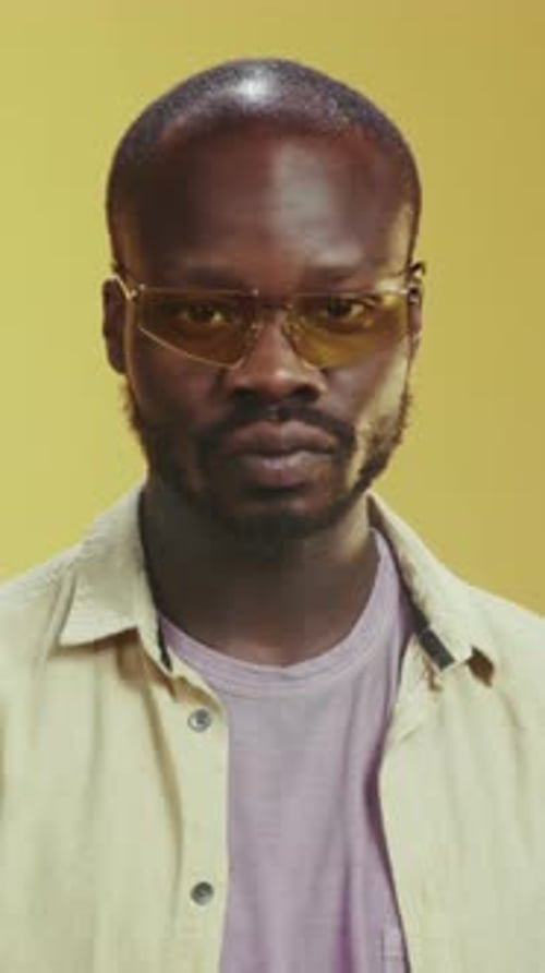 Fashionfocused Portrait of Composed Man Wearing Vibrant Clothing and Reflective Ambiance in Studio