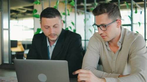 Two Professionals Collaborate in an Office Discussing and Planning Over a Laptop The Focus is on