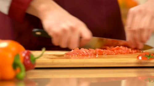 Chefkoch hackt rote Tomaten. Ein Mann hackt Tomaten mit einem Messer, um Tomatensauce zuzubereiten
.
