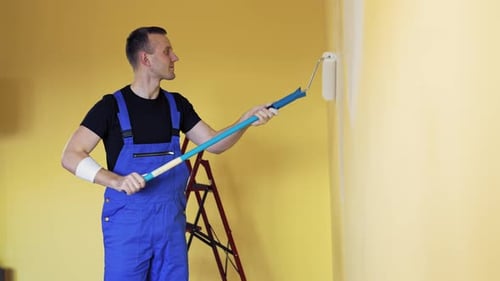 Mann dekoriert Zimmer im neuen Zuhause. Mann malt Wand während der Hausdekoration mit Rollbürste