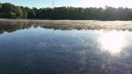 Peaceful Sunrise Over a Misty Lake with Forest Reflection and Calm Water