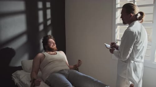 Man in Restraints with Doctor Taking Notes