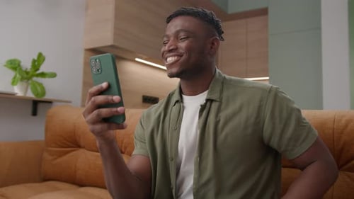 Happy Man Video Calling on Phone at Home