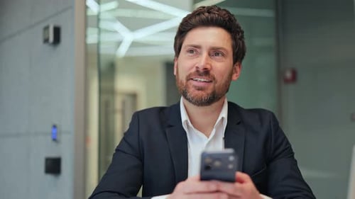 Happy Businessman Using Smartphone in Modern Office