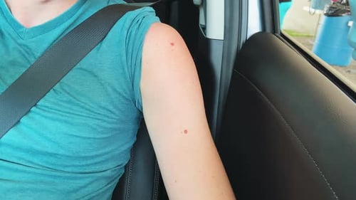 Young Man receives COVID-19 Vaccination shot in his car at a drive through vaccine station.