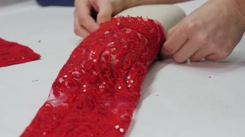 Um alfaiate passando a manga aberta de um vestido de noite em uma oficina de costura