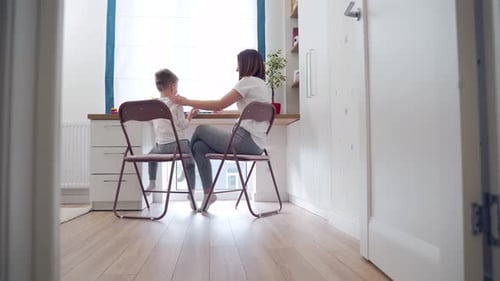 Woman and Boy Painting Pictures Together at Table Indoors