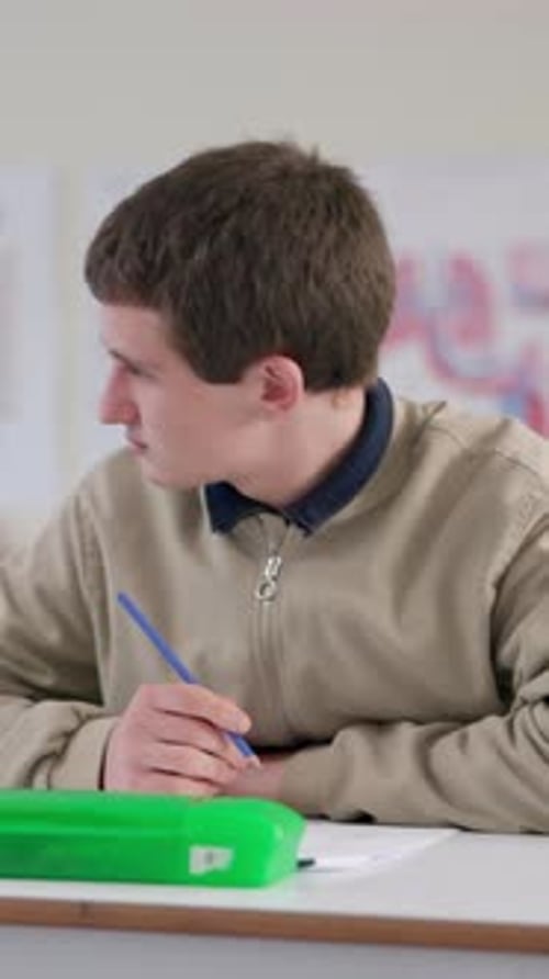 Young Adult Writing in Classroom at Desk