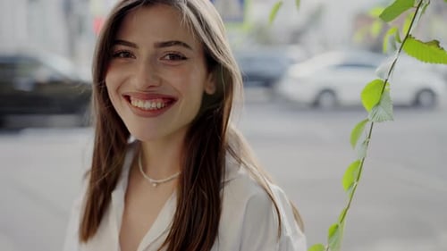 Radiant Young Woman Smiling Brightly on Sunny City Street