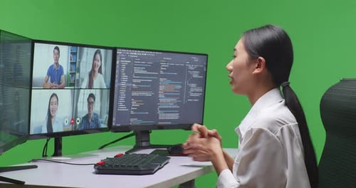 Entwicklerin hat Video, während sie Code mit mehreren Computerbildschirmen im Green Screen Studio schreibt