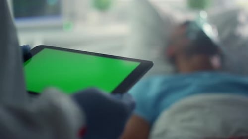 Unrecognized doctor holds chroma key tablet near sick african american patient in hospital