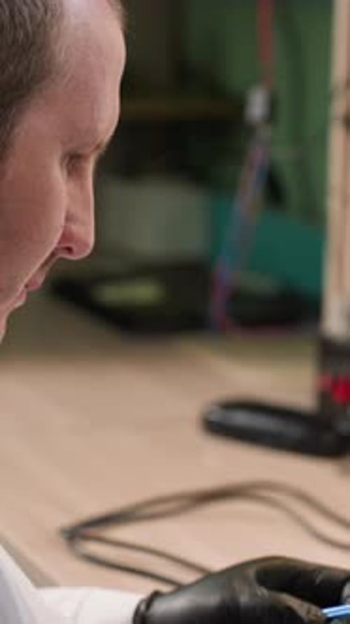 Technician Focusing on Screw and Electronic Component Under Microscope