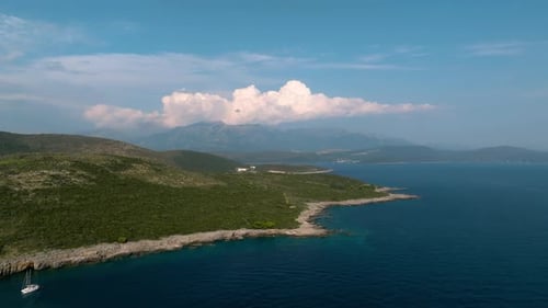 Drone view of a rocky shore by the Adriatic blue sea with mountains in the background, Greece, Croat