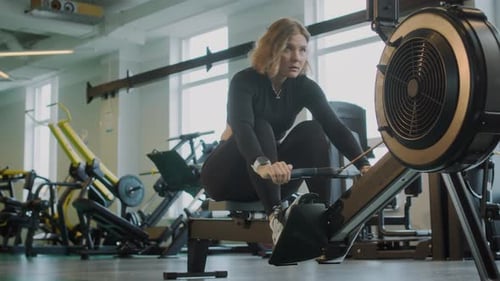 Female Athlete Using Rowing Machine at Gym