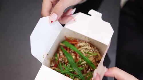 Female Hands Opening Cardboard Box with Chinese Food Asian Udon Noodles