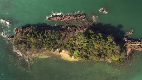 aerial ascending birds eye view of small tropical Island with beach and rocky coastline