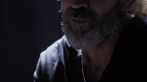 Man with Graying Beard Speaking in the Dark