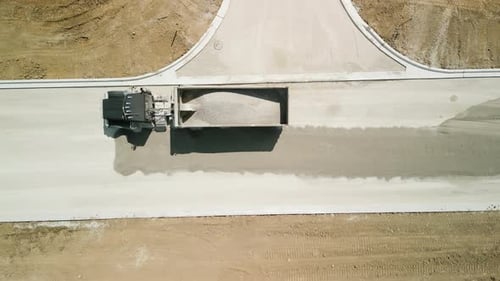 Construction Truck Tipping Dumping Gravel on Road Construction Site Aerial Top View