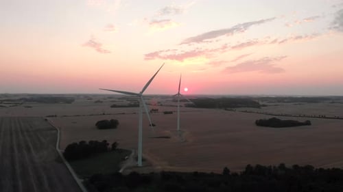 Wind Turbines Rotating at Golden Sunset Over Rural Landscape