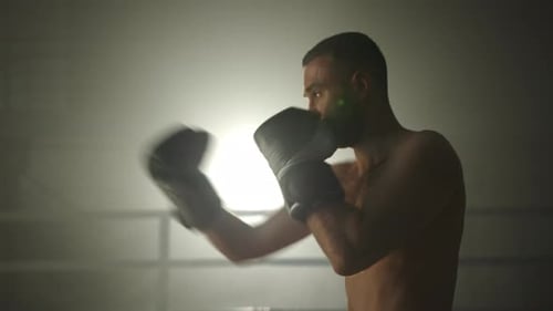 Medium Profile Shot of Middleaged Boxer Performing Shadow Boxing in Gym