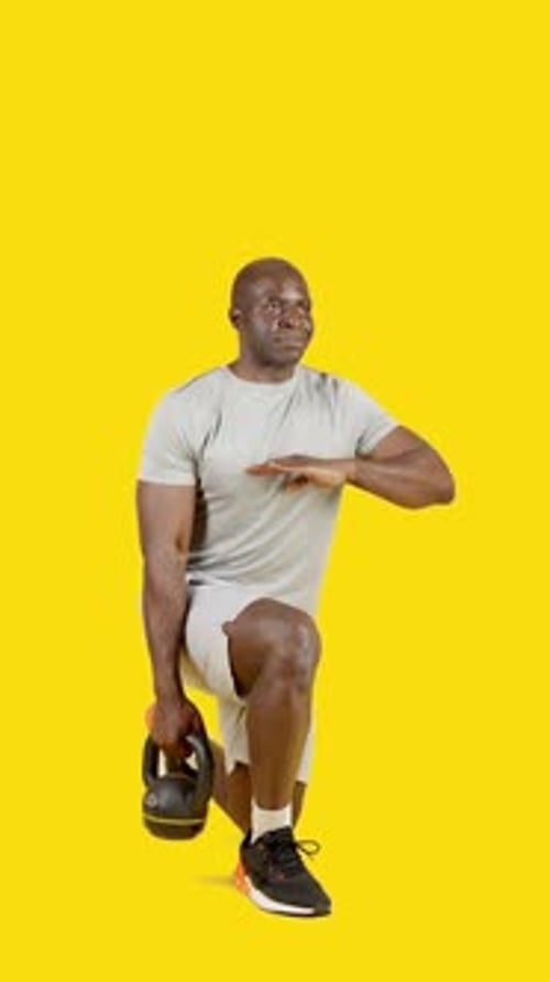 Un deportista africano haciendo estocadas con pesas rusas