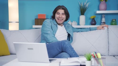 The man laughs when he sees funny events on the laptop.