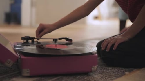 Person Plays Vinyl Record on Pink Record Player