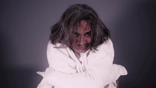 Man in Straight Jacket Sits and Shakes Head