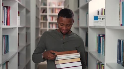 Smiling Man Holds Books in Public Library